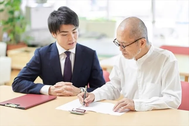 シニア男性に署名を促す若いアドバイザー